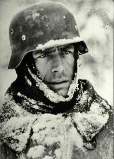 an old black and white photo of a man wearing a helmet with snow on it