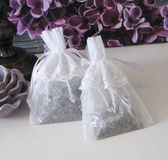 two bags filled with tea sitting on top of a table next to a vase and purple flowers