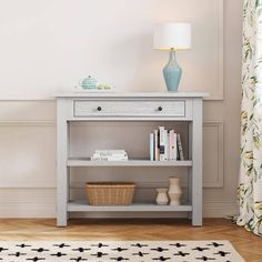 a white shelf with books and a basket on top of it next to a lamp