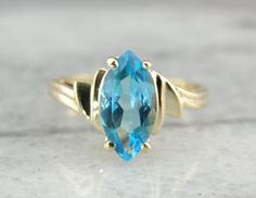 "Classic and stately, this ring is constructed of 14 karat yellow gold, and features a gorgeous richly blue Topaz in the center surrounded by sweeping shoulders of polished gold. Material: 14 Karat Yellow Gold Gem: Blue Topaz 2.08 Carats Size of Ring: 7.25 Marks: \"14K\" Stamped on inside band SKU#: Y4K6CP-D Each piece has been identified and graded by a Graduate Gemologist who has been certified by the Gemological Institute of America (GIA). We have four brick and mortar storefronts in Maine, M Gold Topaz Ring, Topaz Rings, Rings White Gold, Gold Topaz, Topaz Engagement Ring, Brick And Mortar, Rings Gold, Rings Engagement, London Blue Topaz