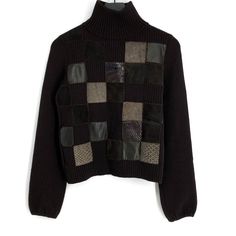 a black sweater with patchwork on the front and back, hanging from a hanger