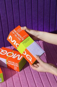 two boxes of orange and pink colored food on a table with purple wall behind them