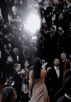 the back of a woman's head as she walks down a red carpet in front of photographers