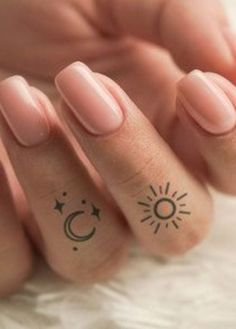 two fingers with sun and moon tattoos on them, one has a star and the other has a crescent