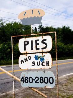 a sign that says pies and such on the side of the road with trees in the background