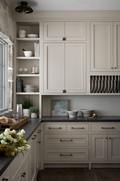 a kitchen filled with lots of white cupboards and counter top space next to a window