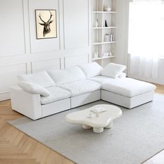 a white couch sitting on top of a wooden floor next to a table in front of a window