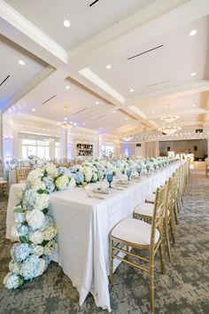 a long table with white and blue flowers on it is set up for a formal function