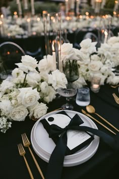 a black and white table setting with flowers, candles and place settings on the tables