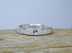 This 3mm wide sterling silver ring is hand-hammered with a rustic texture and set with a 2mm Yogo Sapphire. Perfect for stacking or as a simple accent to a any style. Sizes 4 to 9 are available with a note at checkout. Yogo Sapphire, Boho Wedding Ring, Bozeman Mt, Casual Rings, Rustic Texture, Hammered Silver Ring, Silver Rings With Stones, Sterling Silver Wedding Band, Silver Clay