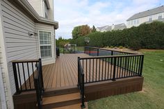 a wooden deck with black railing next to a house