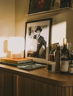 a table topped with bottles and glasses next to a framed photo on the wall above it