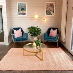 a living room with two blue chairs and a coffee table in front of a window