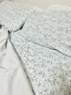 an unmade bed with white sheets and blue flowers