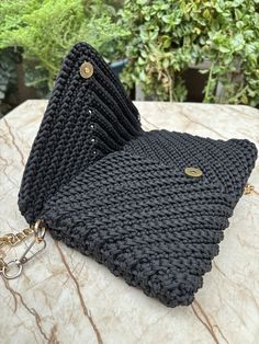 a black knitted purse sitting on top of a table next to a keychain