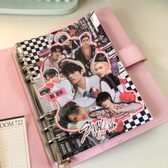 a pink notebook with an image of bts on the cover and some stickers attached to it