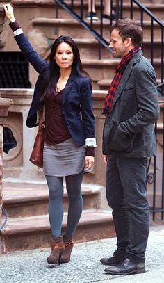 a man and woman standing next to each other in front of stairs with their hands up