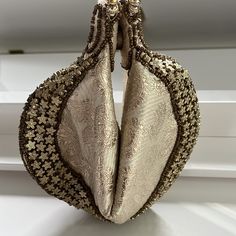 Subtle Paisley Fabric Fortune Cookie Purse. Golden Beaded Bag Gold Metallic. Zip Top, Folds In Like A Fortune Cookie Shape. Two Beaded Round Handles. Gold Star Bead Accents. Comes In Original Cloth Envelope. Excellent Condition, No Flaws Found. Clean Interior. Approximate Flat Lay Measurements: When Closed: 7” Wide, 8.5” Long When Open: 10” Wide, 6” Tall Comes From A Smoke And Pet-Free Home. Embellished Pouch Clutch For Reception, Evening Potli Bag With Gold Embroidery, Elegant Evening Bag With Gold Embroidery For Reception, Evening Gold Embroidered Potli Bag, Luxury Festive Bags With Pearl Handle, Elegant Embroidered Pouch For Formal Occasions, Luxury Potli Bag With Gold Embroidery For Wedding, Beige Hand Embellished Bag For Wedding, Hand Embellished Beige Bag For Wedding