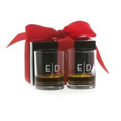 two shot glasses with the word ed on them in front of a red ribbon and black box