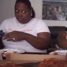 two women sitting on a couch eating pizza