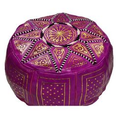 a round purple ottoman with gold and black designs on the top, sitting in front of a white background