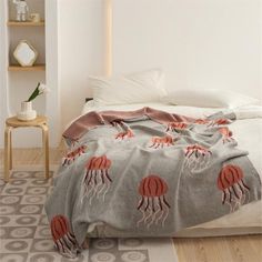 a bed covered in a blanket with red jellyfish on it