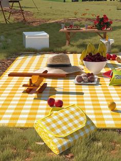 a picnic table set up in the grass with apples, bananas and other food on it