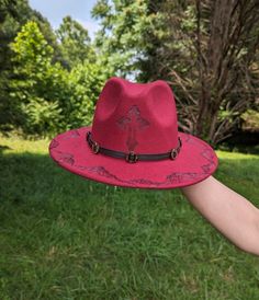 This fedora makes a great nature inspired addition to any wardrobe. The vivid burgundy material burns a gorgeous shade of black allowing the design to stand out. A cross is intricately burned and shaded by hand with a pyrography machine on the crown of the hat. Detailed mountains are burnt along the entire circumference of the top brim. All my designs are original and completely freehanded. For a beautiful finishing touch the hat is adorned with a faux leather black hatband. Hat Materials: 65%cotton 35% polyester Hat fits most women with an adjustable tie band inside *Disclaimer* Colors may vary slightly from screen to screen Red Brimmed Festival Costume Hats And Headpieces, Red Brimmed Festival Costume Hat, Red Brimmed Costume Hat For Festival, Red Brimmed Costume Hats And Headpieces For Festivals, Red Curved Brim Costume Hat For Festivals, Red Costume Hat With Curved Brim For Festival, Red Western Felt Hat For Festival, Red Fedora Hat For Festivals, Red Wide Brim Hat For Festival