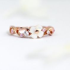 A beautiful rose gold wreath ring featuring a mother of pearl flower adorned with CZ diamonds in white and pink! The gems are exquisitely and securely hand-set by experienced artisan.  Wear this every day and especially with the matching necklace, a classic white, blue, or black little dress for the most dainty look!  ♥ Perfect gift for you and your loved one! ♥ Materials:  - 925 Sterling Silver in Rose Gold - Mother of Pearl - CZ diamond Dimensions:  - 4mm Mother of Pearl Flower  [The Materials] All products are made with high quality hypoallergenic nickel-free  925 real silver in 14k, 18k or rose gold finish. Unlike the thin plated silver or plated gold ones which you would normally find in the market, they will stand the time of wear and would be like new again after a simple polish! Rose Gold Flower-shaped Cubic Zirconia Rings, Rose Gold Flower-shaped Rings With Cubic Zirconia, Rose Gold Cubic Zirconia Flower Promise Ring, Rose Gold Cubic Zirconia Flower Ring As A Gift, Rose Gold Wreath, Black Little Dress, Pearl Wreath, Wreath Ring, Wreath Rings