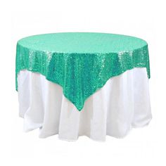 a green and white table cloth on top of a round table with sequins