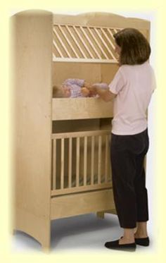 a woman standing in front of a wooden bunk bed with a baby on it's side