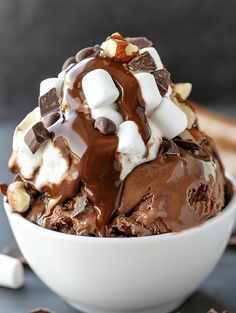 an ice cream sundae with chocolate and marshmallows in a white bowl