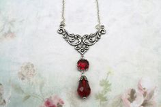 Silver Art Nouveau Necklace- Dark Academia Necklace- Vintage Inspired 1920's Necklace- Red Glass Teardrop Necklace- Ren Faire- Great Gatsby Hanging from a silver plated centerpiece  Is a red square glass framed stone with a  Red faceted teardrop  with a silver bead cap The necklace is 16 inches with a 3 inch extension chain  that has a red Swarovski bicone crystal   The chain is a dainty  antiqued silver link chain The centerpiece is 1 1/2 inches wide and the drop is 2 1/2 inches from the top of the centerpiece.  The red drop is 1 1/4"  It arrives in a gift box with a bow Red Victorian Necklace For Anniversary, Classic Red Teardrop Necklace, Classic Handmade Red Necklace, Red Drop Necklaces For Formal Occasions, Vintage Red Teardrop Jewelry, Classic Red Teardrop Pendant Necklace, Vintage Dangle Drop Necklace For Gift, Vintage Drop Necklace For Gift, Red Handmade Victorian Necklace