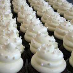 cupcakes with white frosting and pearls on them are lined up in rows