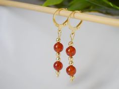 Carnelian Dangle Earrings Gold, Red Orange Carnelian Gemstone Huggie earrings, Carnelian Jewelry, Natural Stone, Jewelry Gift For Her. ⭐ Handmade beautiful classy gold plated dangle earrings with natural carnelian stone in orange red. ⭐ Materials used:-  Earrings  ✧ High quality gold plated 304 stainless steel lever back hoop earrings, gold plated stainless steel beads,  Hoop Size:- 14.5 x 12 mm ✧ Natural stone carnelian beads.  Toatal length of earrings including hoop 40mm (4.0cm) ⭐ Packing: Carefully packaged and ready to give as a gift. If you want to add a note, please leave me a message with your order. ⭐ We look forward to personal inquires, do not hesitate to contact us. ☘️As these are natural gemstones, the color may vary and the pair ordered will be shipped based on stock. Please Red Agate Earrings With Natural Stones, Carnelian Gemstone Dangle Earrings, Carnelian Dangle Earrings With Natural Stones, Carnelian Natural Stones Dangle Earrings, Red Agate Dangle Earrings, Carnelian Dangle Jewelry With Matching Earrings, Red Carnelian Pierced Earrings, Red Carnelian Gemstone Earrings, Amber Carnelian Earrings With Ear Wire