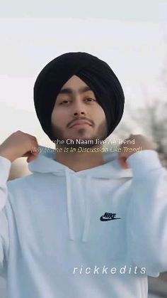 a man wearing a white hoodie and black turban is posing for the camera