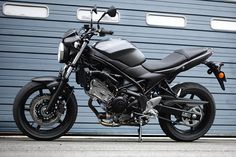 a black motorcycle parked in front of a garage door