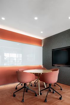 two chairs and a table in front of a flat screen tv on a wall behind them