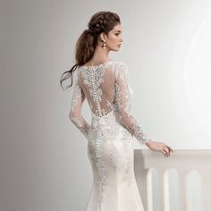 the back of a wedding dress with sheer sleeves and beaded details on the neckline