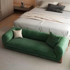 a green couch sitting on top of a bed next to a night stand in a bedroom