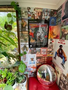 a red chair sitting in front of a wall covered with posters and plants next to a window