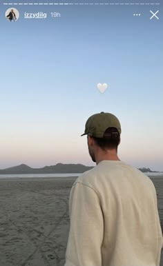 a man standing on top of a sandy beach next to the ocean under a blue sky