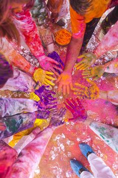 several people with their hands in the middle of a colorful circle