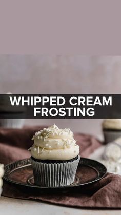 a cupcake on a plate with whipped cream frosting in the background and text overlay that reads whipped cream frosting