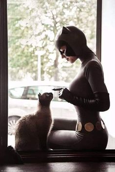 a woman in cat costume standing next to a cat