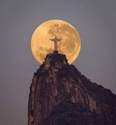 the full moon is seen behind a statue on top of a mountain in rio cristianoa