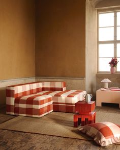 an orange and white checkered couch sitting on top of a rug next to a window