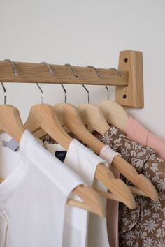 several shirts hanging on wooden hangers in a closet