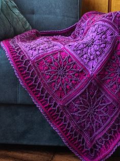 a purple crocheted afghan sits on a couch