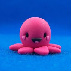 a pink toy octopus sitting on top of a blue surface